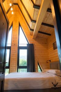een bed in een kamer met een groot raam bij Hidden Chalet in Tarcău-Gheuca