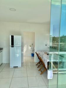 une cuisine blanche avec un réfrigérateur et une table à l'intérieur dans l'établissement Apto inteiro, novo,2 quartos, silencioso, à Presidente Soares