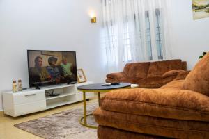 a living room with a couch and a tv at Appartement de 3 chambres avec jacuzzi in Cotonou