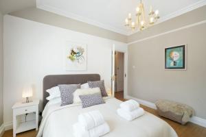 a white bedroom with a bed with pillows and a chandelier at Hidden Gem in Finchley