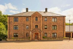 a large brick building with a red door at The Pentland Apartment in Penicuik