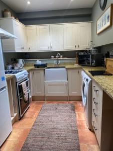 a kitchen with white cabinets and a sink at Everley Cottage in Scarborough