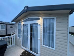 a house with a porch with a door on a deck at Oak Green- Top award winning caravan! in Gristhorpe +8 photos