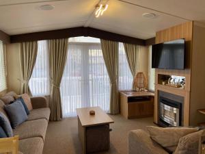 a living room with a couch and a fireplace at Oak Green- Top award winning caravan! in Gristhorpe