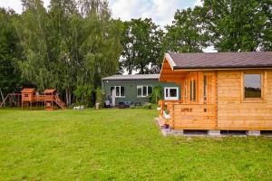 a log cabin in a yard with a playground at Nowy domek z podgrzewanym basenem na wyłączność in Braniewo
