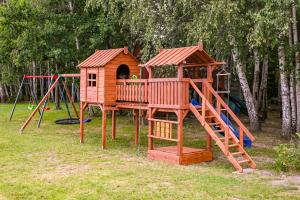 a wooden playground with a slide and a play house at Nowy domek z podgrzewanym basenem na wyłączność in Braniewo