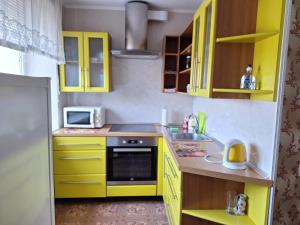 a yellow kitchen with a sink and a microwave at Saulriets in Liepāja