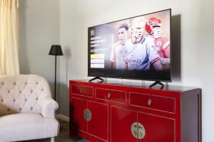 a flat screen tv on top of a red dresser at Paradies für die kleine Familie direkt am See in Stocksee