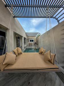 a swinging bed in a house with a pool at radhwan chalet رضوان شالية in Qurayyah
