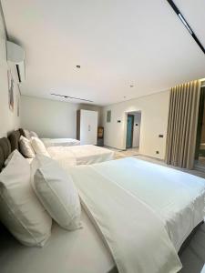 a large bedroom with two beds with white pillows at radhwan chalet رضوان شالية in Qurayyah +26 photos