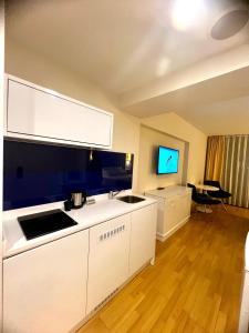 une cuisine avec des armoires blanches et une télévision à écran plat dans l'établissement Orbi city apartment, à Batoumi