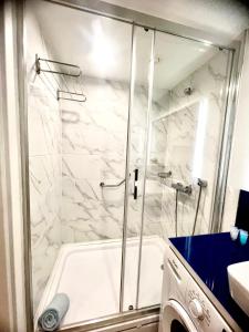 une douche avec une porte vitrée dans une salle de bain dans l'établissement Orbi city apartment, à Batoumi 6 autres photos