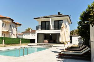 a house with a swimming pool and an umbrella at Villa Sarisli 2 in Ortaca