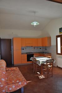 a living room with a table and a kitchen with orange cabinets at Villa Bella Vista in Capo Vaticano