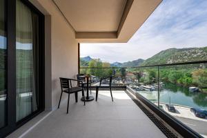 a balcony with a table and chairs and a view of a river at Hotel De‘Andros Virpazar in Virpazar