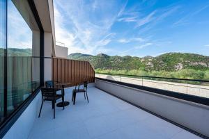 a balcony with a table and chairs and a view of mountains at Hotel De‘Andros Virpazar in Virpazar
