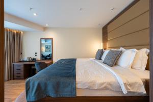 a bedroom with a large bed and a desk at Hotel De‘Andros Virpazar in Virpazar