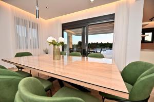 a dining room with a wooden table and green chairs at Villa Donatus in Murvica +124 photos