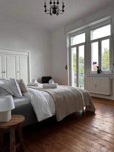a white bedroom with a bed and a chandelier at SweetLeopold1 in Bad Kreuznach