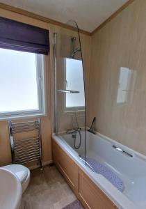 ein Badezimmer mit Badewanne, Toilette und Waschbecken in der Unterkunft The Knightsbridge, Boulevard, Seal Bay Resort in Selsey