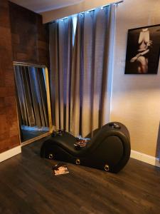 a black couch sitting on the floor in front of a window at Love Room l'Audacieuse in Saint-Quentin