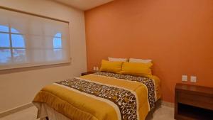 a bedroom with a bed with orange walls and a window at Palacio Huatulco - 5C in Santa Maria Huatulco
