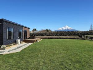 a black house with a lawn and a mountain in the background at Peachy On Pembroke stunning mountains views with 9 hole Mini Putt in Stratford