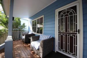 - une terrasse couverte à l'avant avec 2 chaises et une porte dans l'établissement Kookaburra Cottage 71 Straight St HH, à Hat Head