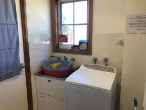 une cuisine avec une machine à laver et une fenêtre dans l'établissement Kookaburra Cottage 71 Straight St HH, à Hat Head 9 autres photos