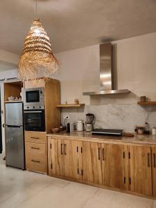 a kitchen with wooden cabinets and a chandelier at Villa Nour Kélibia in Kelibia +57 photos