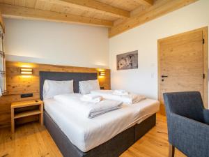 ein Schlafzimmer mit einem großen weißen Bett und einem Stuhl in der Unterkunft Chalet Pettneu am Arlberg - Top 4 in Pettneu am Arlberg