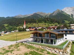 ein Haus in einem Dorf mit Bergen im Hintergrund in der Unterkunft Chalet Pettneu am Arlberg - Top 4 in Pettneu am Arlberg