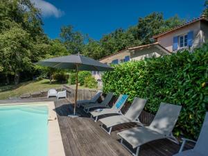 a group of chairs and an umbrella next to a swimming pool at La Maison sur la Colline in Laprade