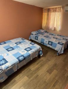 a bedroom with two beds and a wooden floor at Departamento a 2min de Playa la Madera in Zihuatanejo