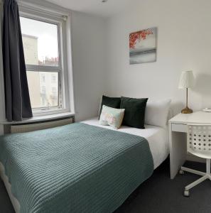 a bedroom with a bed and a desk and a window at LORD MERIT GUEST HOUSE KING'S CROSS GRAYS INN ROAD in London