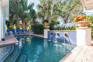 a swimming pool in a house with blue chairs and trees at Clearwater Beach Splendor - Weekly Beach Rental in Clearwater Beach