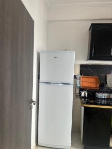 a white refrigerator in a kitchen next to a counter at Martil Bel appartement lumineux, situé à seulement proche de la plage, idéal pour les vacances en famille ou entre amis, proche commerces in Martil