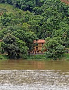 a house sitting on the side of a river at Pousada Mirante Do Lago in Lindóia