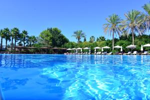 a large swimming pool with umbrellas and palm trees at Green Paradise Resort in Otranto