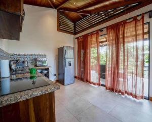 a kitchen with a refrigerator and some windows at Modern Two Story Beach house in Puerto Viejo