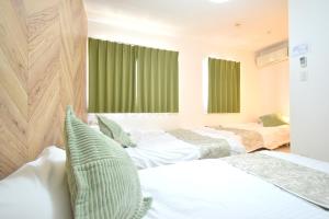東京にあるKamata332 蒲田駅の2LDKアパートメント 羽田8min 品川8minの緑のカーテンがかかった部屋にベッドが2つ