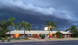Un edificio con palmeras frente a una calle. en Country Roads, en Peak Hill