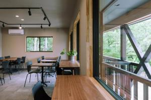 a dining room with tables and chairs and a window at DAHARA n-1 in Minami Aso