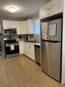 a kitchen with white cabinets and a stainless steel refrigerator at Cozy Basement Apartment in Shediac