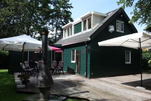 een groen huis met stoelen en parasols op een terras bij Holiday Home De Zuwe - Loosdrecht in Kortenhoef