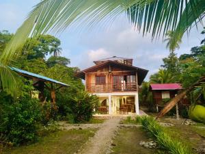 a wooden house with a palm tree in front of it at Ecolodge Vientos de Yubarta in Nuquí