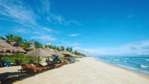 une plage avec des chaises et des parasols et l'océan dans l'établissement Heritage AnBang, à Hội An