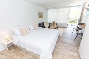 a white bedroom with a large bed and a living room at Luxury Boho 1bedroom 8 Minutes From Disney Free Parking in Kissimmee