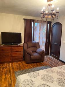a living room with a chair and a flat screen tv at Hotel Casa Victoria in Antigua Guatemala
