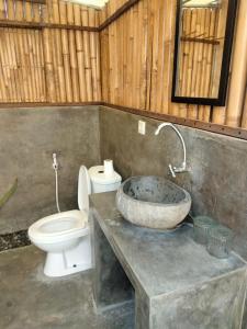 a bathroom with a stone sink and a toilet at Mountview Bali in Kubupenlokan